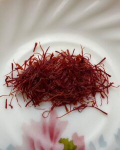 Premium Kashmiri Mongra Saffron threads on a white plate, showcasing vibrant color and quality.