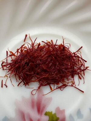 Premium Kashmiri Mongra Saffron threads on a white plate, showcasing vibrant color and quality.